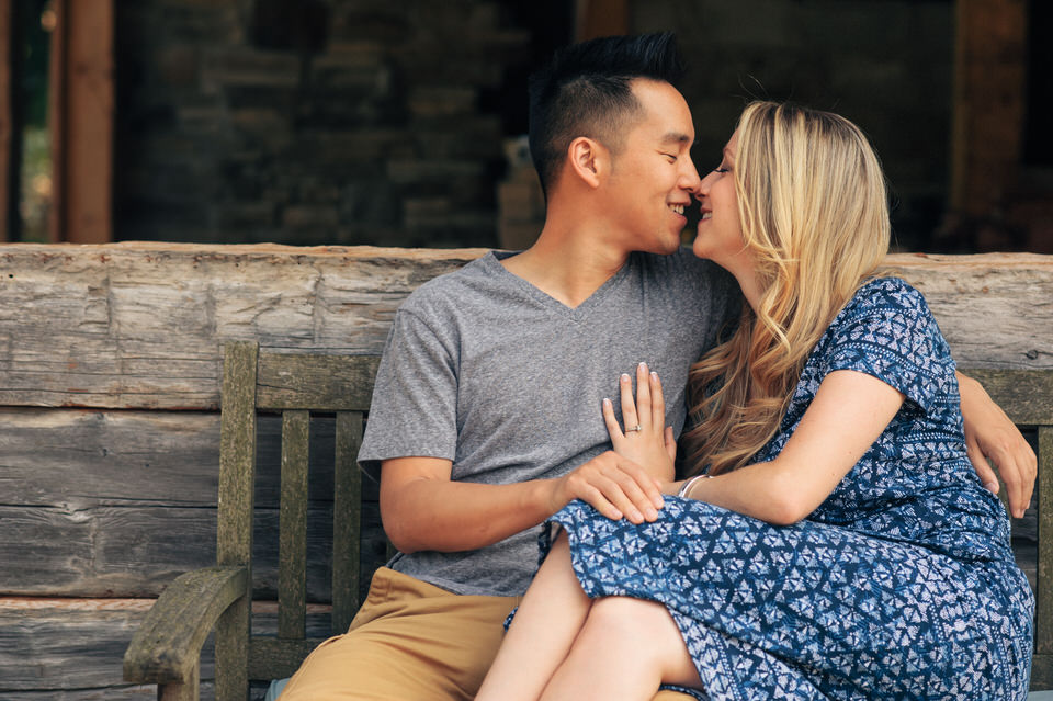 Engagement photo of couple cuddling on a wooden bench
