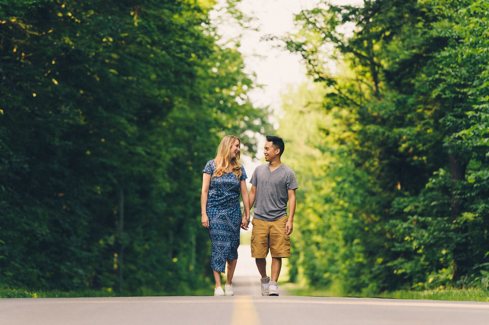 Engaged couple walking hand in hand on a country road