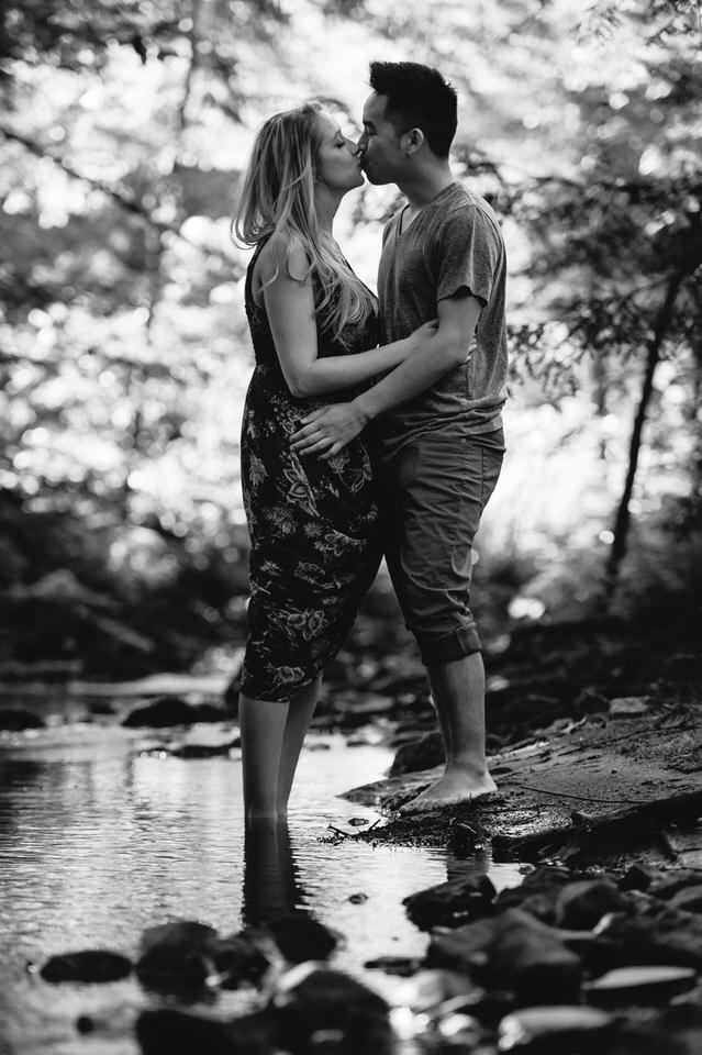 Couple kissing on the banks of a creek in the woods