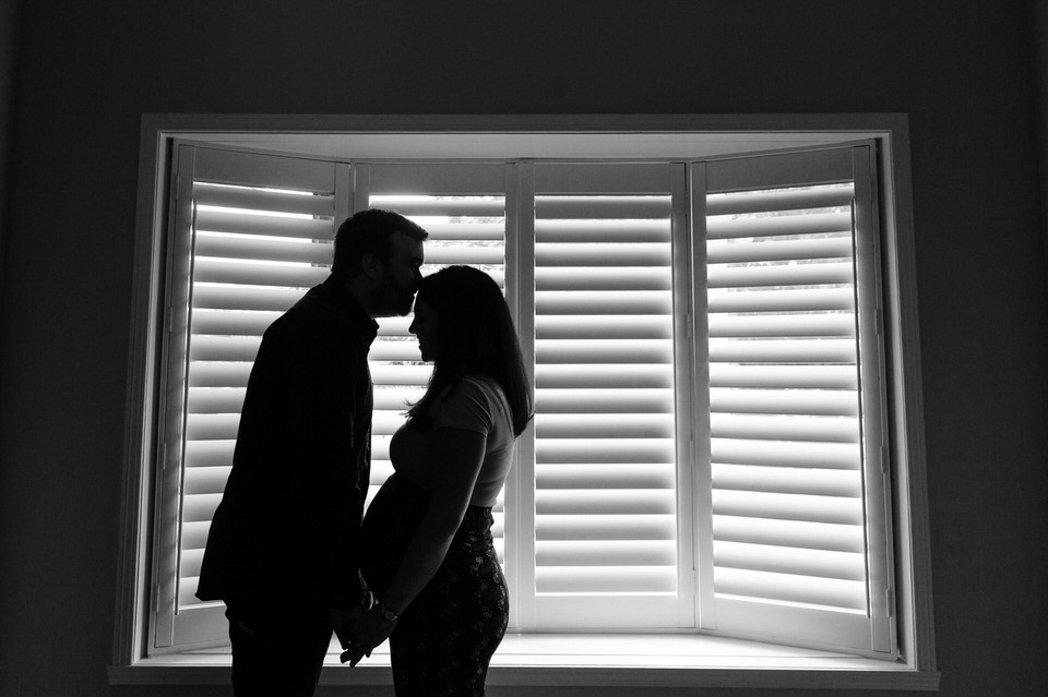 Indoor maternity portrait in front of a window