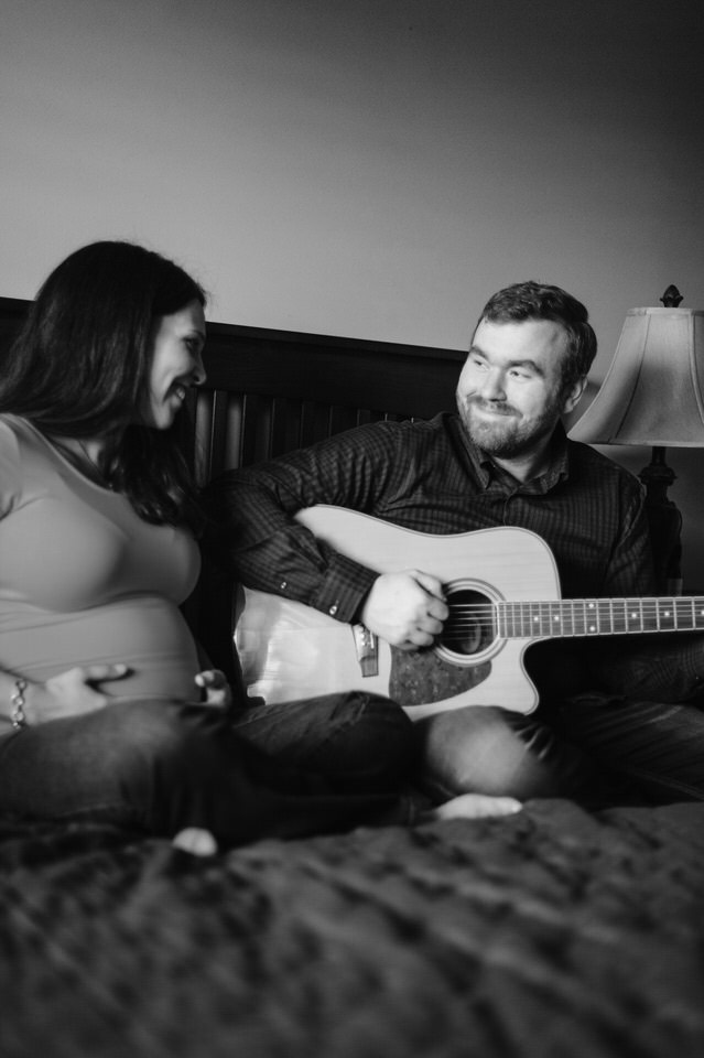 Pregnant woman listening to husband play guitar