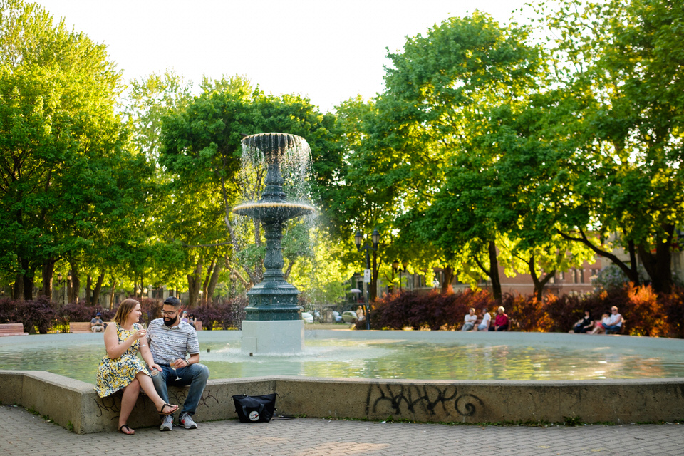 Newly engaged couple sitting on side of fountain in Saint-Louis square