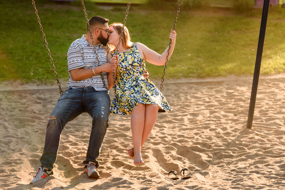 Engagement photo on a swing set at playground at sunset