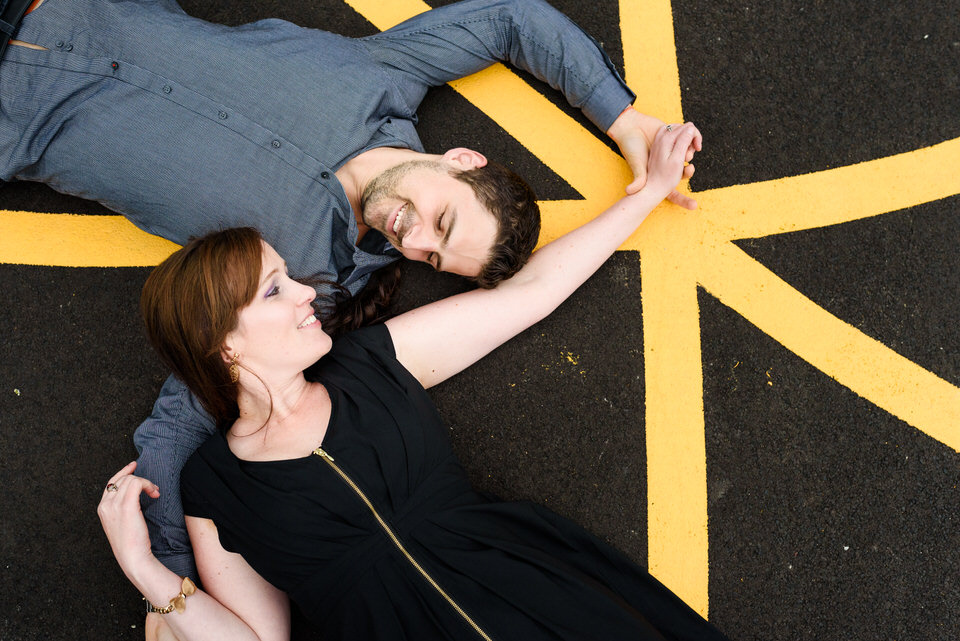 Couple lying on concrete with yellow lines near them