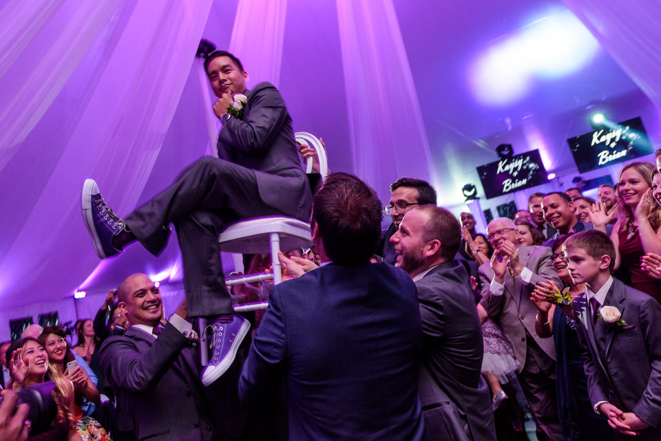 Wedding guests carrying groom on a chair