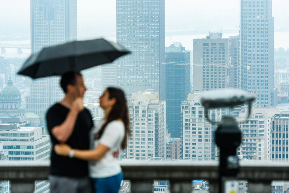 Couple under umbrella with Montreal skyline behind