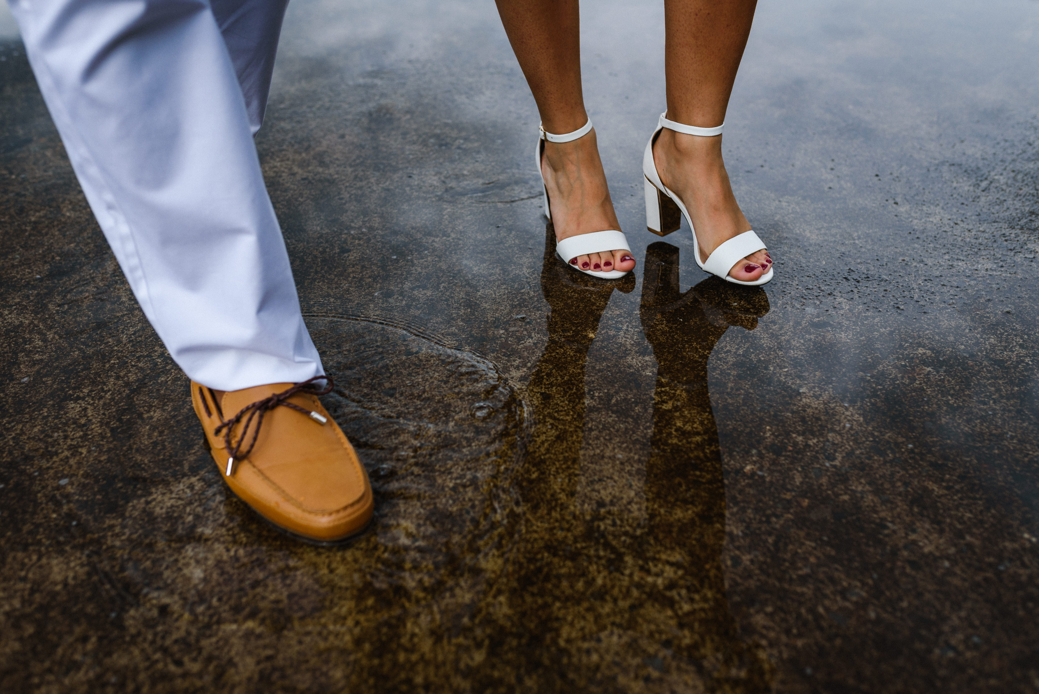 Close up of man and women's feet walking through puddle