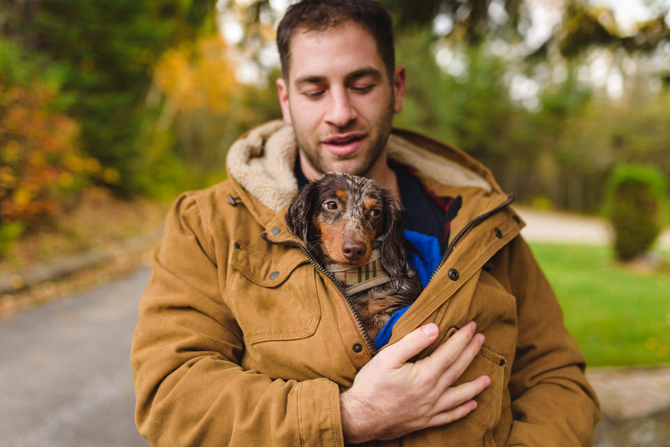 Man carrying his dog wrapped in his coat