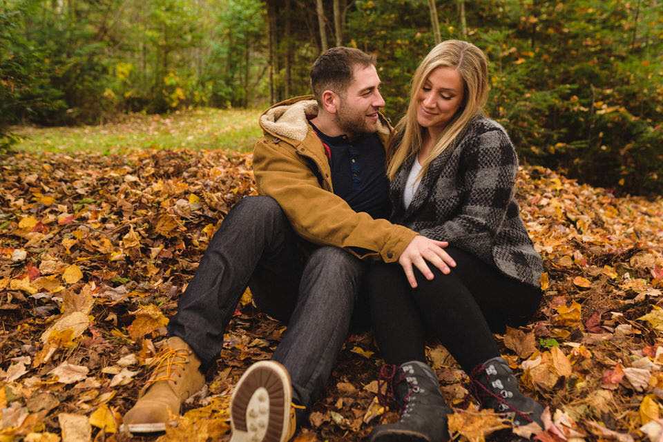 Engaged couple sitting in fall leaves