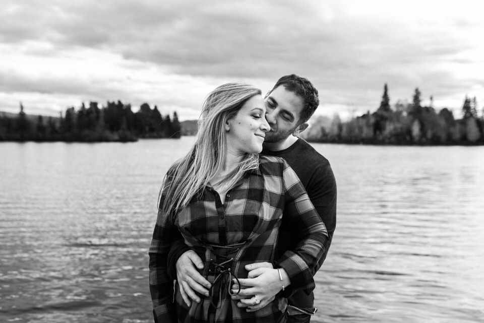 Black and white engagement photo in front of a lake