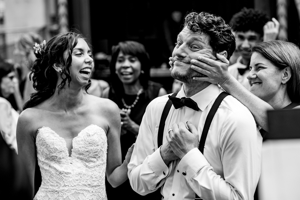 Groom's cousin pushing his cheeks into a smile as bride laughs
